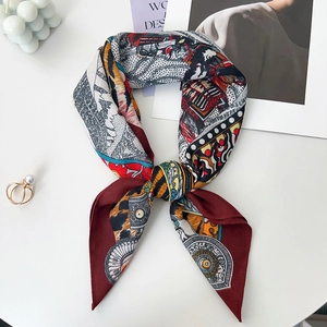 Detailed view of luxury silk scarf with red border and artistic patterns in a bow tie fold