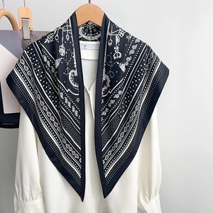 Detail of printed silk scarf with paisley and chain patterns on a white shirt