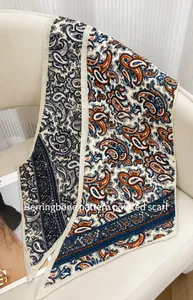 Détail de motifs chevrons et cachemire sur foulard en soie posé sur fauteuil cuir