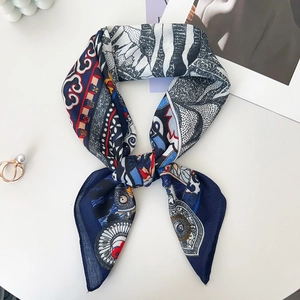 Detailed view of leopard print silk scarf tied neatly with pearls on a white surface
