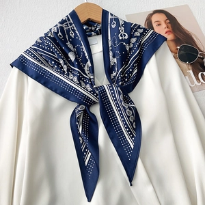 Detailed view of dark blue silk scarf with paisley and chain patterns on a white shirt