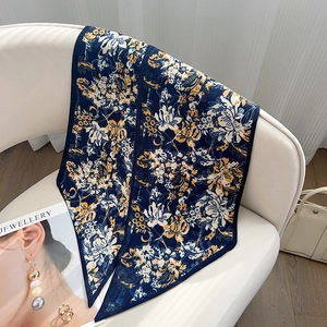 Détail d'un foulard en soie bleu marine à fleurs drapé sur un fauteuil blanc élégant
