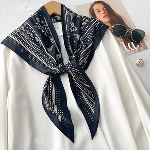 Detail of elegant paisley silk scarf knotted on a white shirt with golden key patterns