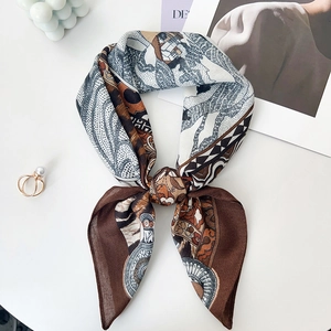 Close-up of leopard print silk scarf tied in a bow with elegant pearls on white surface