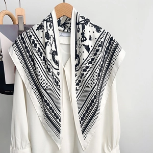 Elegant black and white printed silk scarf styled with a minimalist white V-neck shirt