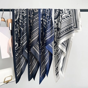 Elegant silk scarf with paisley pattern and chain print hung on a black metal rack