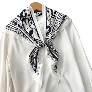 Elegant black and white paisley silk scarf with key pattern styled on a white shirt