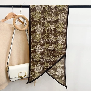 Fashionable floral thin silk scarf in earthy tones paired with a beige sweater and bag