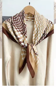 Detail of herringbone pattern square scarf draped on beige sweater for winter fashion