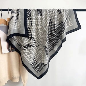 Close-up of houndstooth scarf texture with black border hanging on a wooden hanger