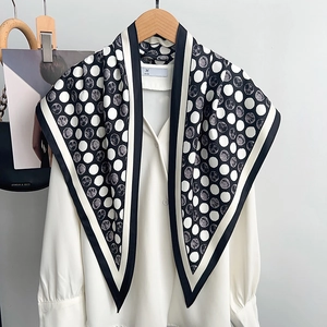 Elegant black and white polka dot silk scarf draped over a white blouse for commute style