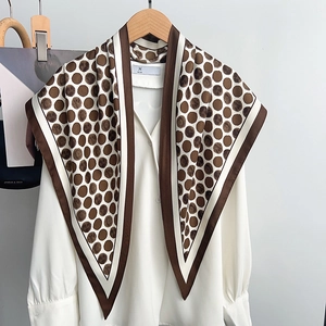 Vintage brown polka dot silk scarf draped over a white blouse for an elegant look