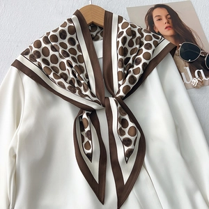 Polka dot silk scarf in brown and white tied on a shirt with vintage accessories