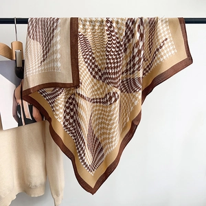 Detail of herringbone houndstooth pattern on brown large square scarf hanging on a rack