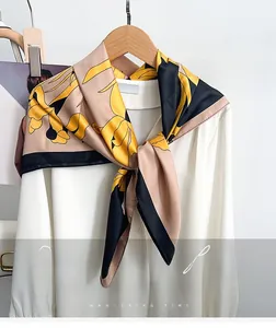 Detail of silk-like floral scarf with yellow pattern tied on a white blouse collar