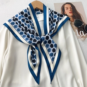 Detail of blue and black polka dot silk scarf styled on a white chiffon shirt collar