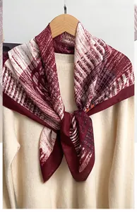 Detail of burgundy herringbone square scarf draped on a knit sweater for autumn style