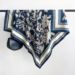 Détail d'un foulard en soie bleu marine et beige aux motifs floraux sur un support