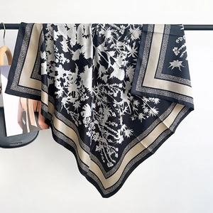 Détails d'un foulard carré en soie avec imprimés floraux noirs et blancs et bordure