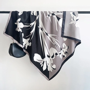 Detail of elegant large silk scarf with gray floral prints hanging on a black rack