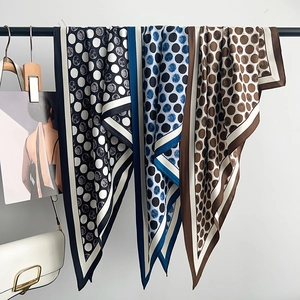 Vintage polka dot silk scarves in brown and navy on a minimalist display with accessories