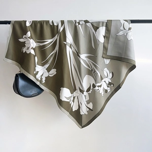 Close-up of olive green silk scarf featuring artistic hand-drawn white iris patterns