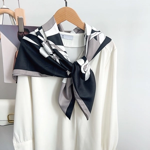 Elegant silk-like scarf with black and white floral print styled on a white shirt