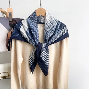 Silk feel scarf with blue abstract stripes worn over a beige sweater on a hanger
