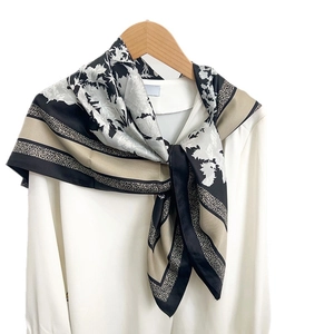 Écharpe élégante en soie à motifs floraux noir et champagne sur un cintre blanc
