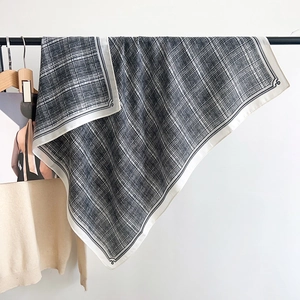 Detail of a large black and white checkered scarf with high-quality stitching and fringe edge
