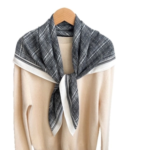 Classic black and white checkered scarf with fringe detail draped on a white sweater