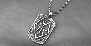 Macro view of rectangular steel pendant with embossed geometric wolf head and hammered texture
