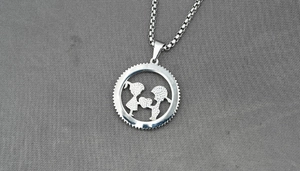Detail of silver couple pendant showing a boy and girl silhouette holding a heart