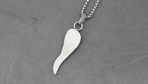 Détail d'un pendentif plume argenté avec texture brossée et collier à chaîne carrée