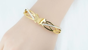 Close-up of golden butterfly bracelet with frosted texture and sparkling crystal pavé