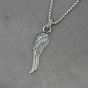 Collier avec pendentif aile serti de cristaux et chaîne box argentée sur fond gris