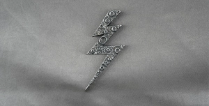Close-up of vintage lightning bolt pendant with rustic lunar surface texture on silk
