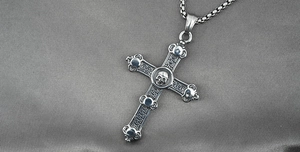 Macro shot of vintage cross pendant with skulls and oxidized steel box chain