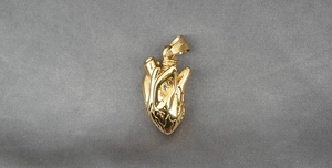 Detailansicht des goldenen anatomischen Herzanhängers mit feiner Textur im Punk-Stil