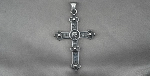 Detailed close-up of a vintage steel gothic cross pendant with a skull center and rivets