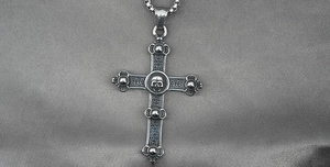 Macro detail of gothic cross pendant with skull motif and vintage steel box chain
