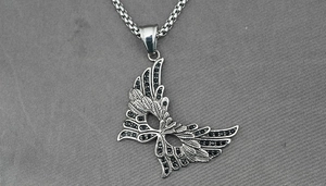 Macro shot of silver winged mask pendant with black zircon inlays on a snake chain