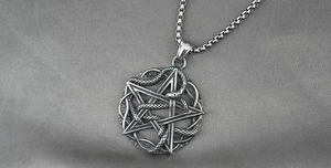 Macro detail of retro stainless steel pentagram star and cobra snake pendant with box chain