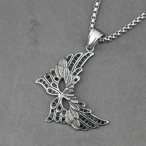 Gothic silver wing pendant necklace featuring black crystals on a grey fabric background