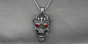 Macro detail of gothic skull pendant with red rhinestone eyes and vintage steel finish