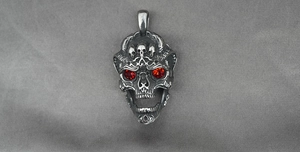 Detailed close-up of a gothic skull pendant with striking ruby red crystal eyes