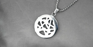Close-up of industrial hollow round pendant with box chain on grey silk background