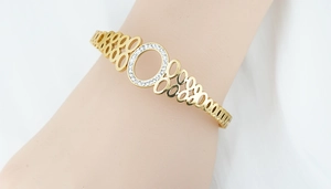 Détail d'un bracelet ajouré doré avec micro-pavage de zircons porté au poignet