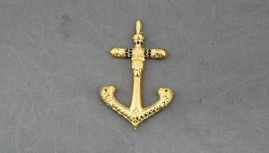Detailed close-up of gold anchor pendant with skull cross and black stones inlay