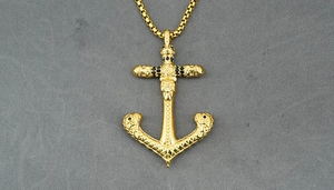 Detailed close-up of golden nautical anchor pendant with skull and black gemstones
